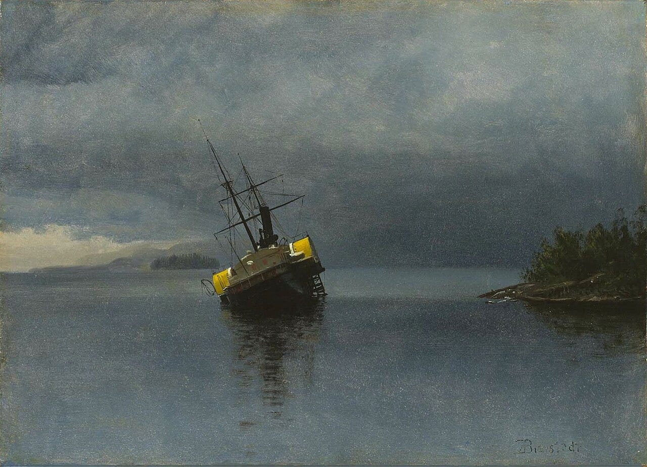 A small steamer listing on a reef in a calm gray bay, her funnel and two masts tilted, with a wooded point of land at the right and her reflection in the still water