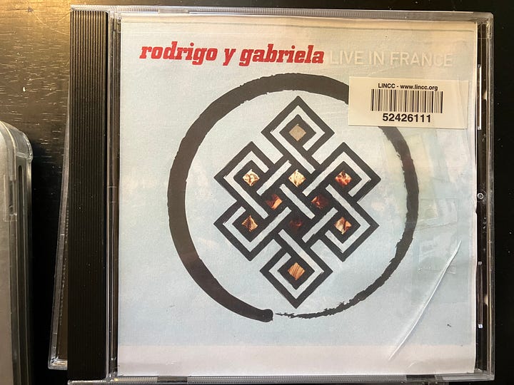Four photos of a compact disc music player and three Spanish music compact discs (CDs)