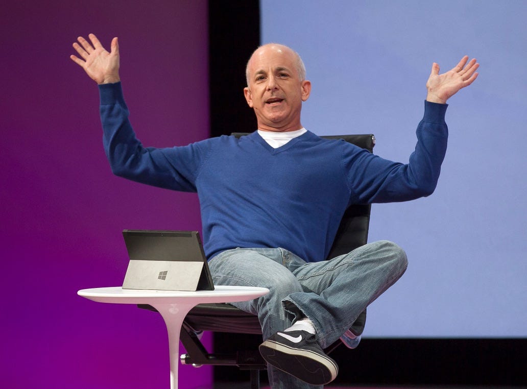 Me sitting in a chair with my arms up. Surface is on a small table with the kickstand out making it possible to watch the screen or do a video conference hands free.