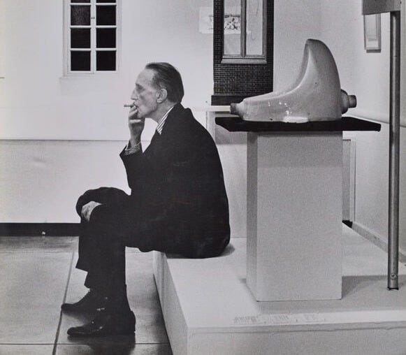 Marcel Duchamp smoking in front of Fountain (1917).