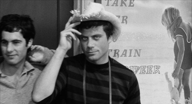 Oliver Reed in a straw hat stares into camera
