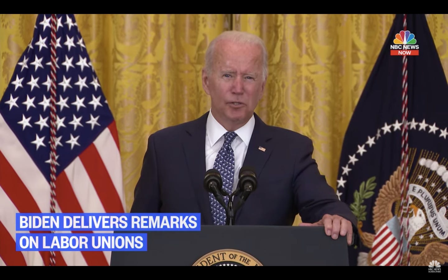 a screenshot of Joe Biden at a presidential podium in front of a US flag and Washington, D.C., flag speaking into a microphone a screenshot of Joe Biden at a presidential podium in front of a US flag and Washington, D.C., flag speaking into a microphone