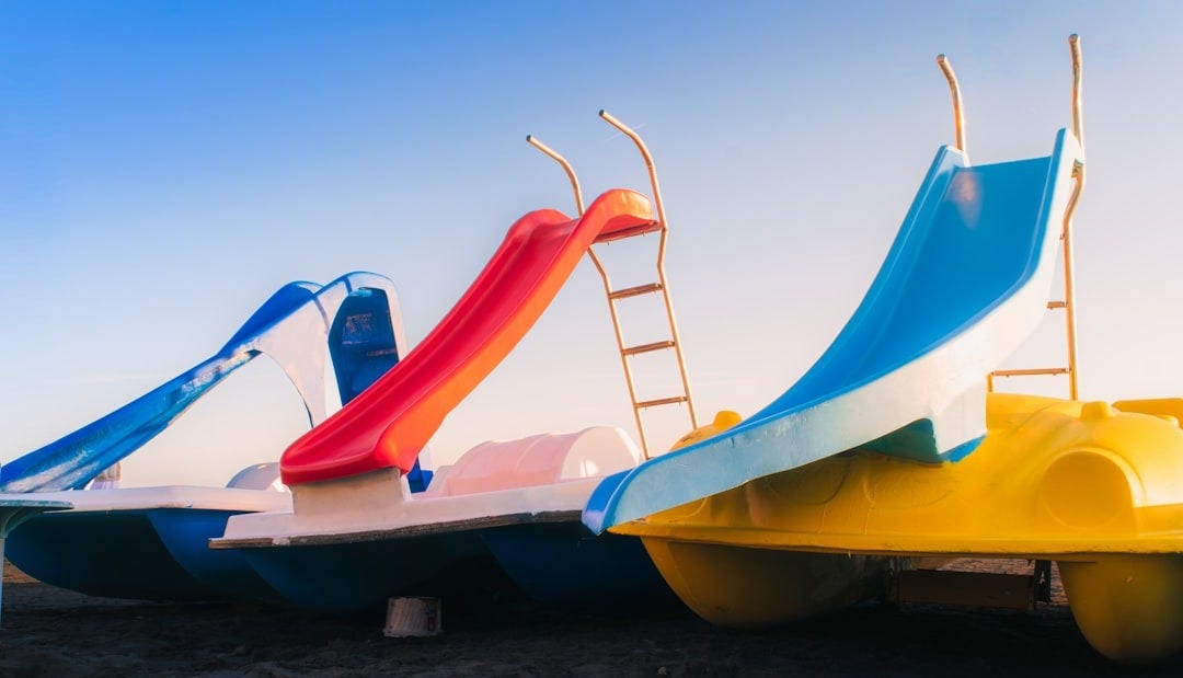 Three colorful pedal boats with slides under a clear sky. Three colorful pedal boats with slides under a clear sky.