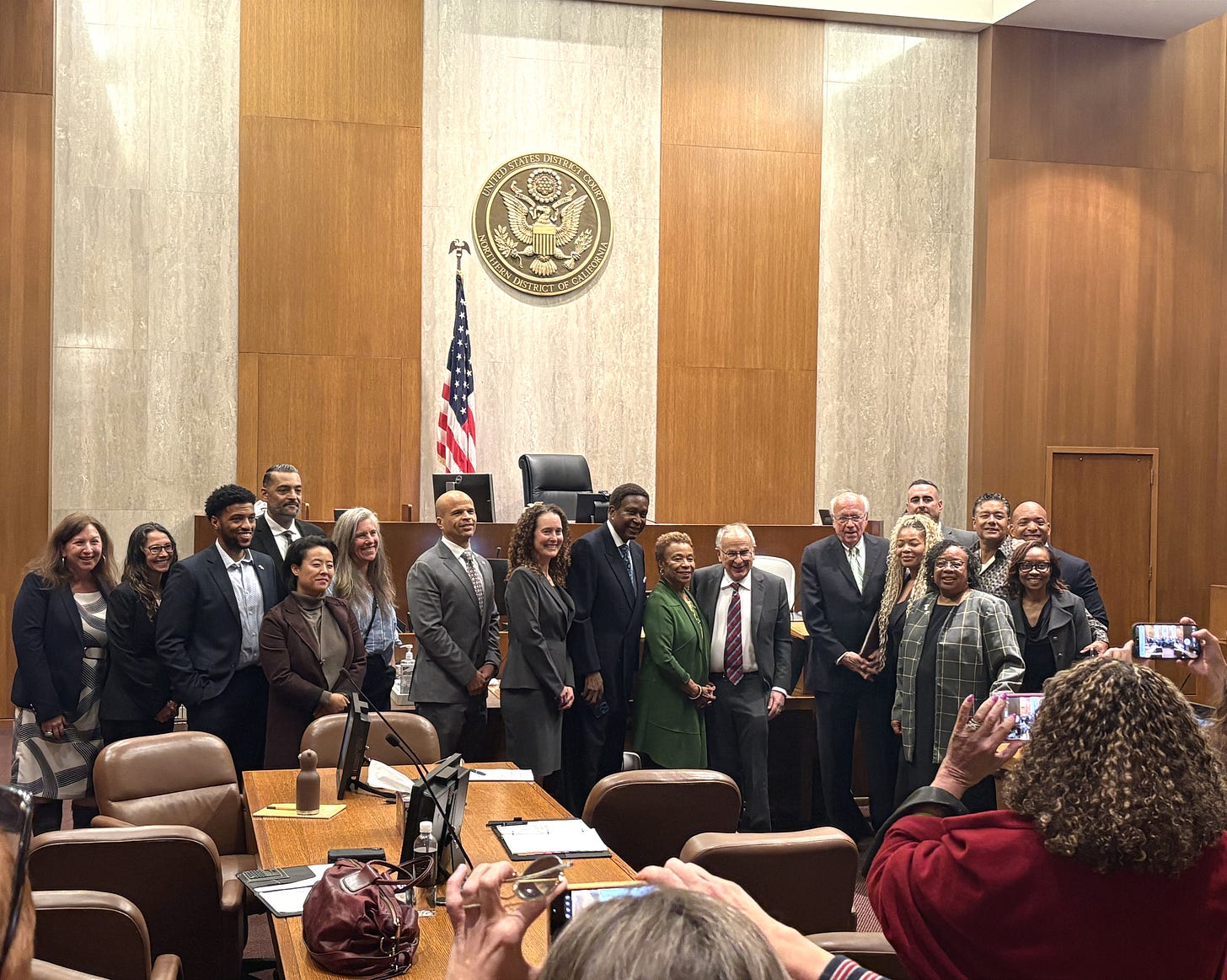 A team effort. From left to right: Robin Busch-Wheaton (Warshaw and Associates), Kristin Burgess (OPD Risk Management Bureau), Kevin Jenkins (Council President), Ricardo Garcia-Acosta (Chair of Police Commission), Charlene Wang (Councilmember), Betsy Lake (Interim City Administrator), Ryan Richardson (City Attorney), Bridgid Martin (Legal Counsel, City Attorney’s office), John Burris (plaintiff attorney), Barbara Lee (Mayor), Jim Chanin (plaintiff attorney), Robert Warshaw (federal monitor), Michelle Phillips (Assistant City Administrator, interim Constitutional Policing Administrator), foreground: Damita Davis-Howard (Director of Public Safety), Jennifer Eberhardt (Social psychologist, Stanford University), background: James Beere (OPD Chief), Ken Houston (Councilmember), Aaron Smith (OPD Deputy Chief Internal Affairs Bureau). Photo by Rajni Mandal, Sept. 29, 2026. A team effort. From left to right: Robin Busch-Wheaton (Warshaw and Associates), Kristin Burgess (OPD Risk Management Bureau), Kevin Jenkins (Council President), Ricardo Garcia-Acosta (Chair of Police Commission), Charlene Wang (Councilmember), Betsy Lake (Interim City Administrator), Ryan Richardson (City Attorney), Bridgid Martin (Legal Counsel, City Attorney’s office), John Burris (plaintiff attorney), Barbara Lee (Mayor), Jim Chanin (plaintiff attorney), Robert Warshaw (federal monitor), Michelle Phillips (Assistant City Administrator, interim Constitutional Policing Administrator), foreground: Damita Davis-Howard (Director of Public Safety), Jennifer Eberhardt (Social psychologist, Stanford University), background: James Beere (OPD Chief), Ken Houston (Councilmember), Aaron Smith (OPD Deputy Chief Internal Affairs Bureau). Photo by Rajni Mandal, Sept. 29, 2026.