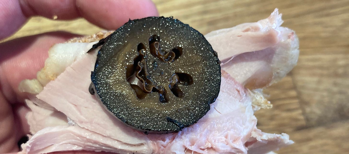 a cross section of a pickled walnut on a piece of roast veal