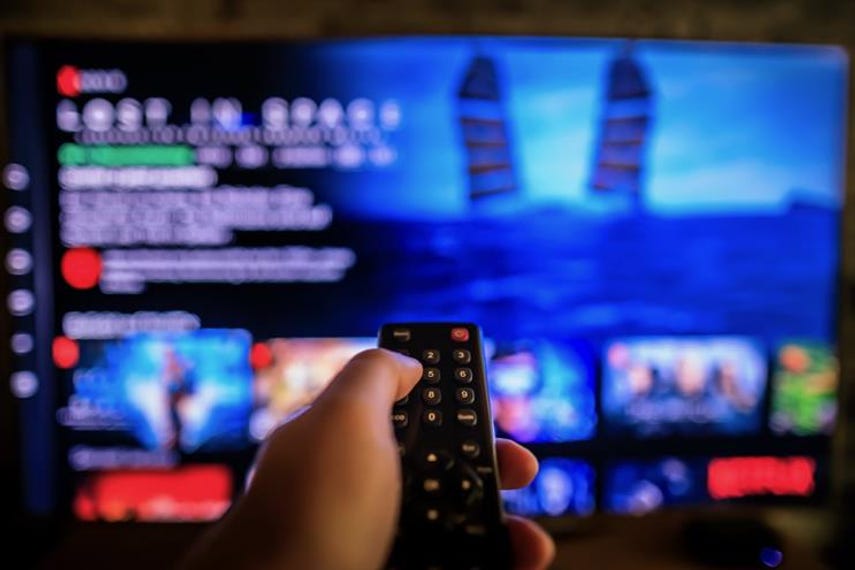 Person holding remote pointing at Netflix