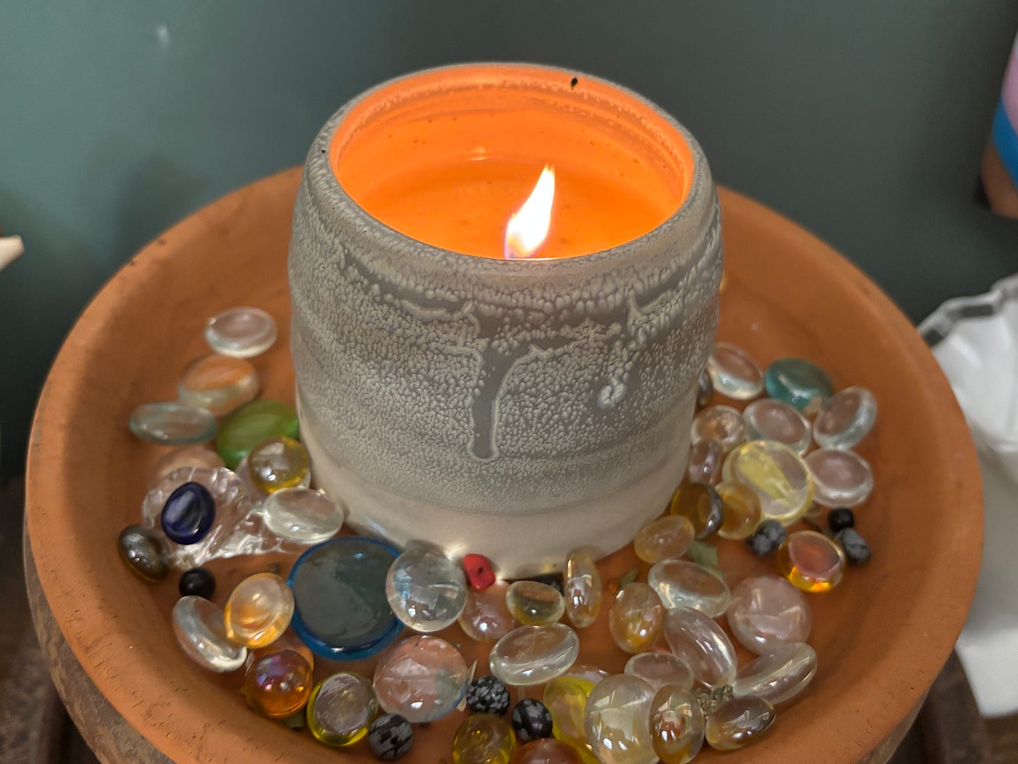 a candle set on a plate of glass beads