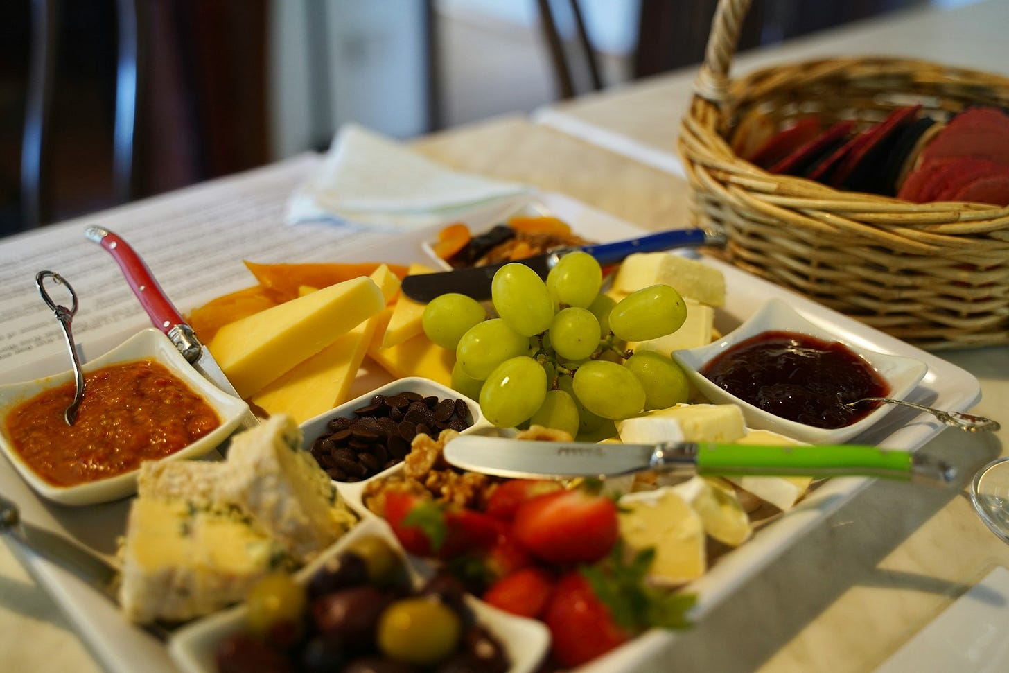 A plate of cheese, fruit, olives, and other snacks.