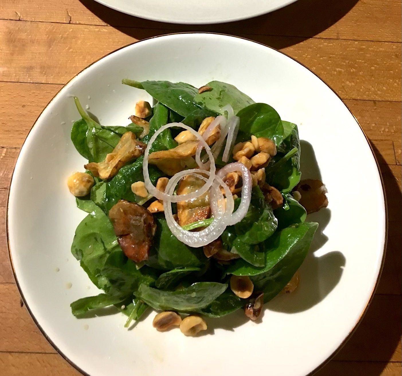 Spinach salad with chopped hazelnuts, sunchokes, and thinly sliced shallots dressed in a warm brown butter vinaigrette.