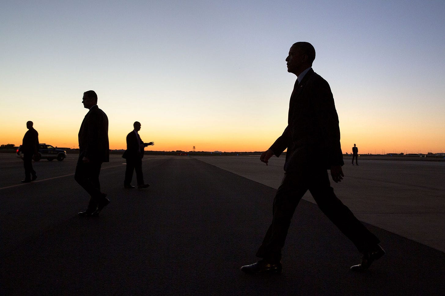 November 4, 2016: A striking silhouette of President Obama, flanked by Secret Service, as he walks across the tarmac to greet a waiting crowd upon arrival at the North Carolina Air National Guard Base. November 4, 2016: A striking silhouette of President Obama, flanked by Secret Service, as he walks across the tarmac to greet a waiting crowd upon arrival at the North Carolina Air National Guard Base.