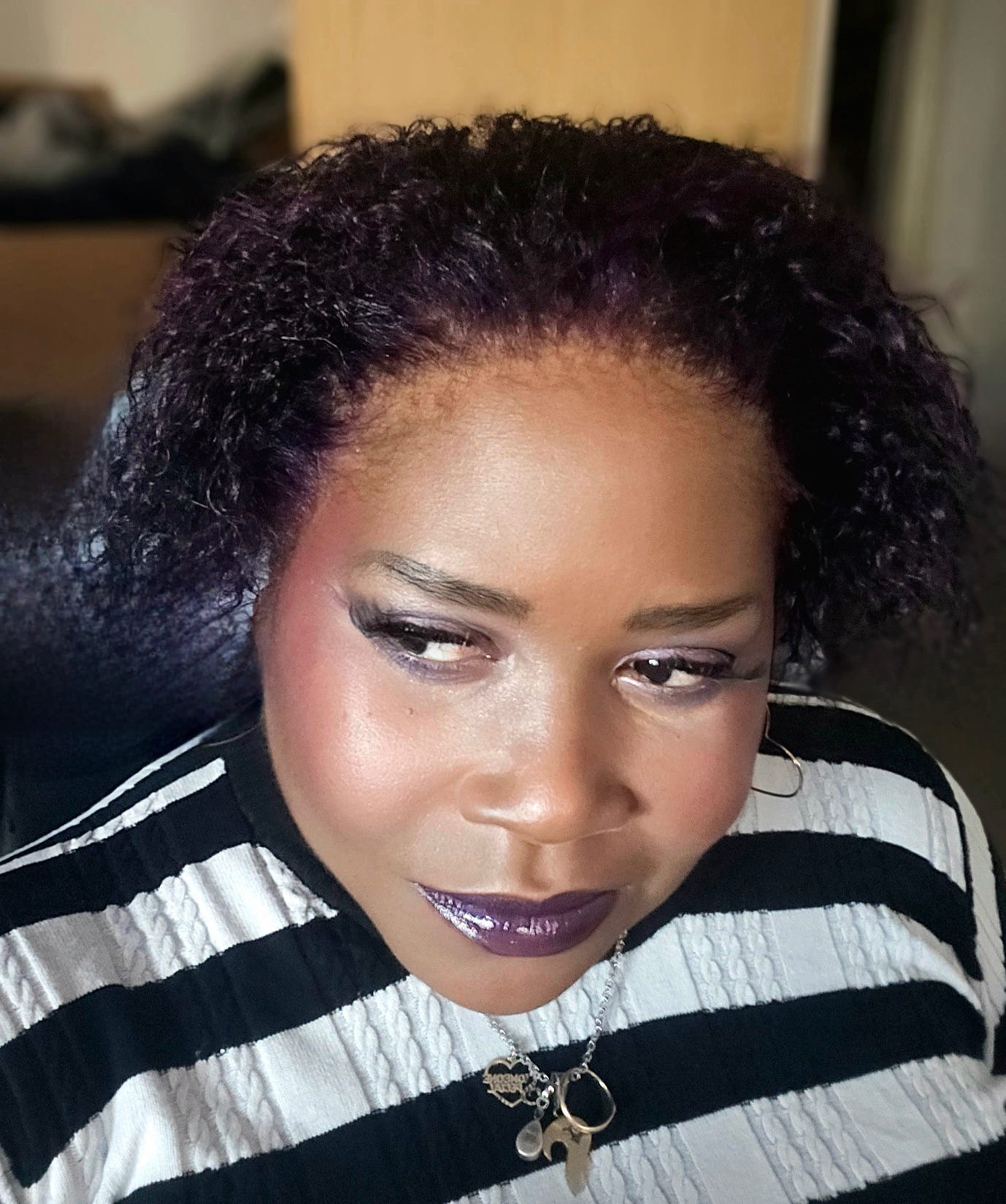 A person with purple hair and black and white striped shirt