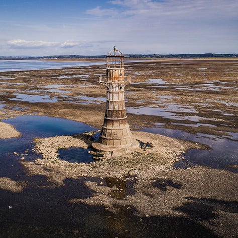 A gallery of three photographs showing different Welsh lighthouses. From left to right: the stark white tower of Nash Point standing on a green clifftop; the red and white striped Point of Ayr lighthouse resting on a sandy beach at sunset; and the rustic, cast-iron Whiteford Point lighthouse surrounded by expansive tidal flats.