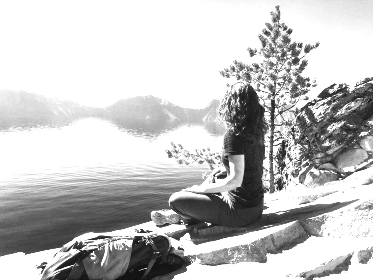Karista at Crater Lake, sitting on a boulder and looking over the lake in meditation