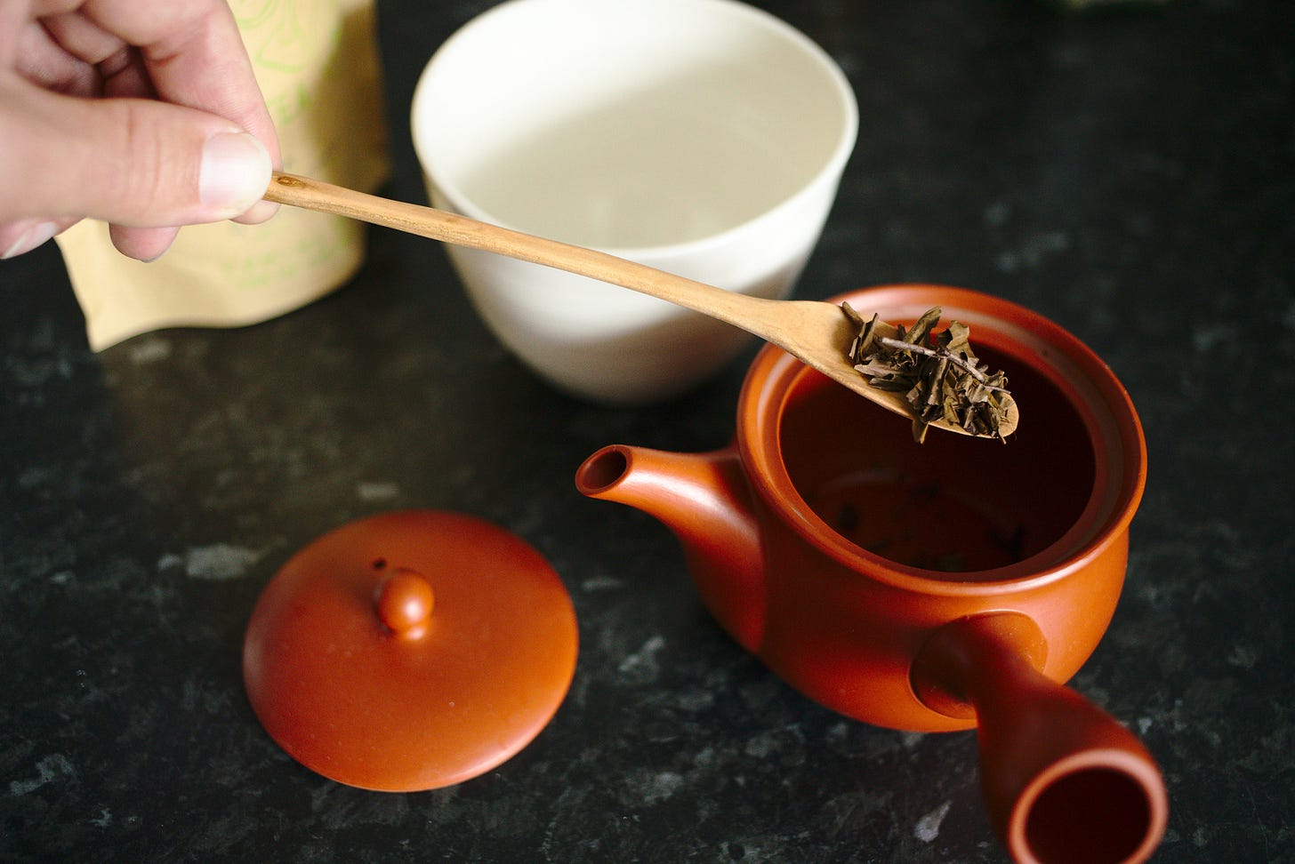 A long cherry tea scoop from our shop, pouring some houjicha tea into our Japanese tea pot.