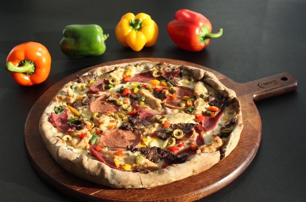 a pizza sitting on top of a wooden cutting board