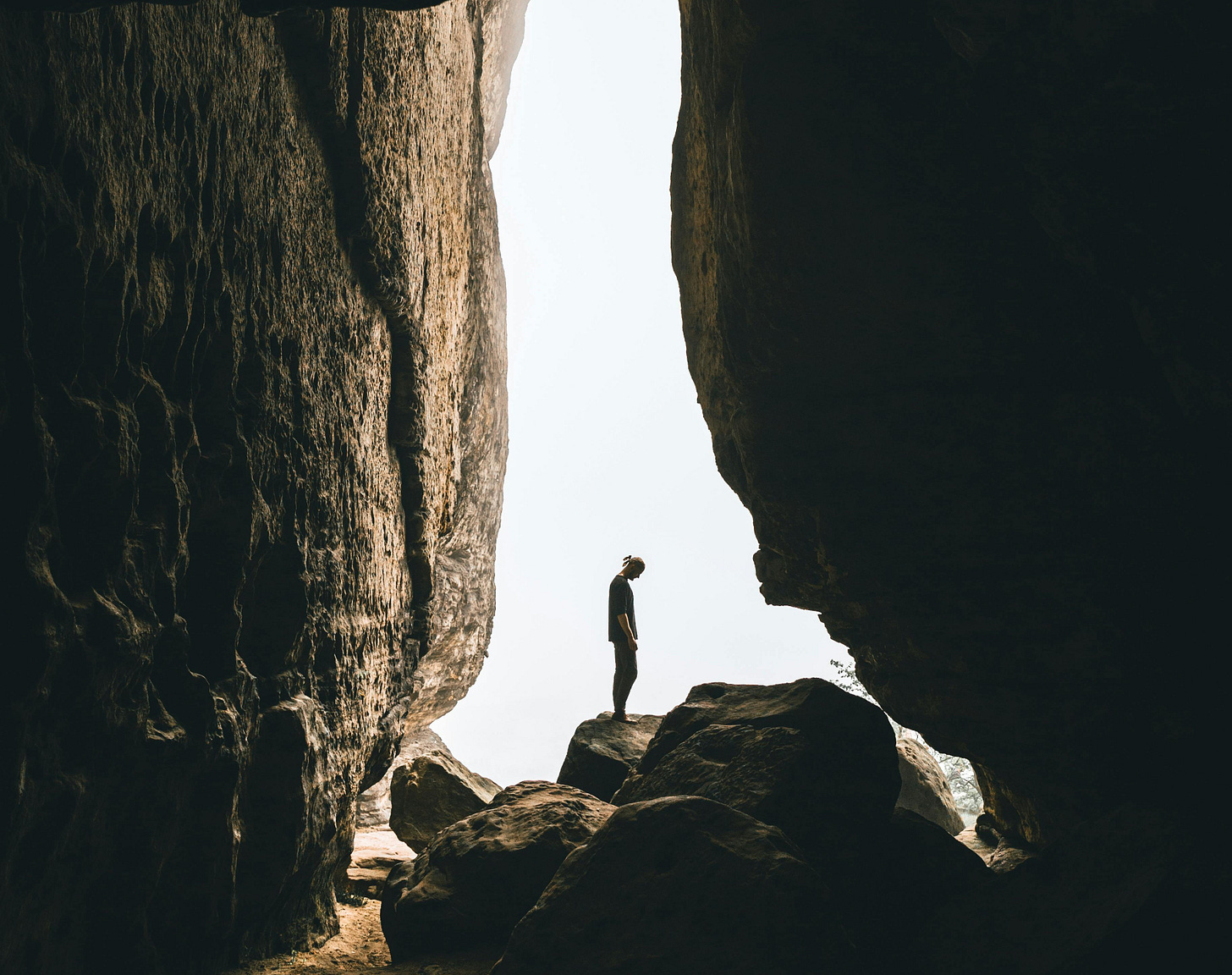 A person stands in the opening of a cave