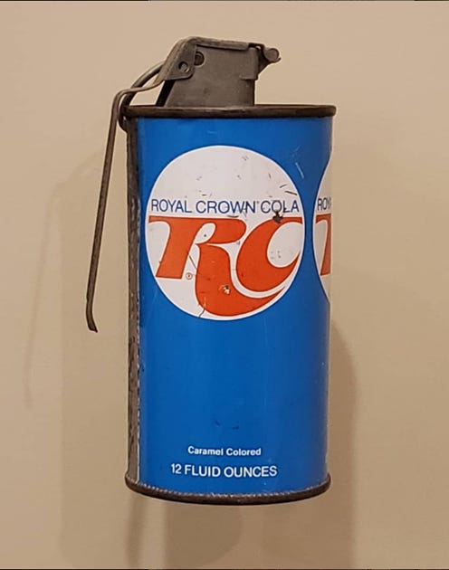 RC Cola can fashioned into a grenade displayed in a museum case.