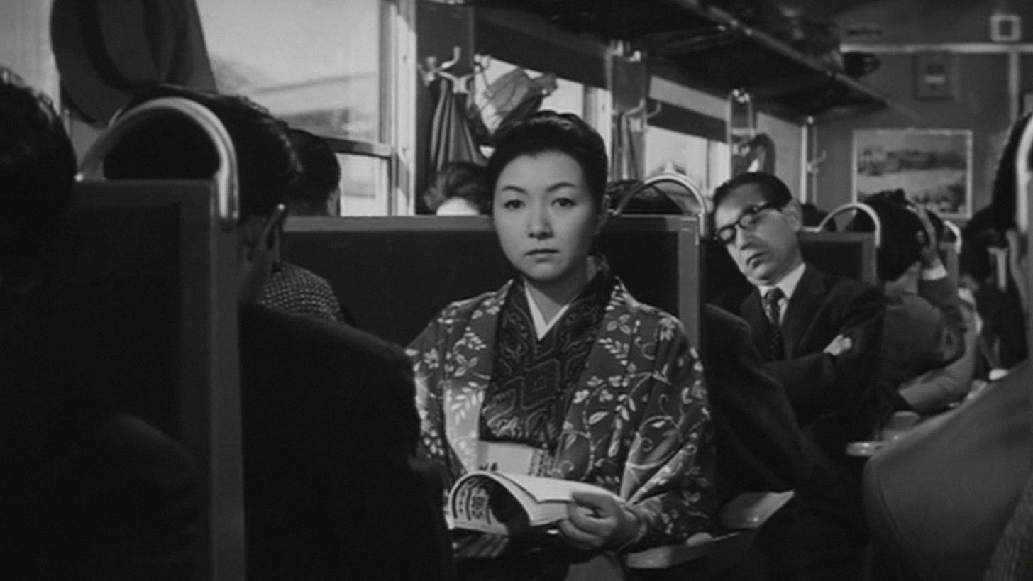 Yearning | Still features Hideko Takamine as Reiko Morita seated on a crowded train.