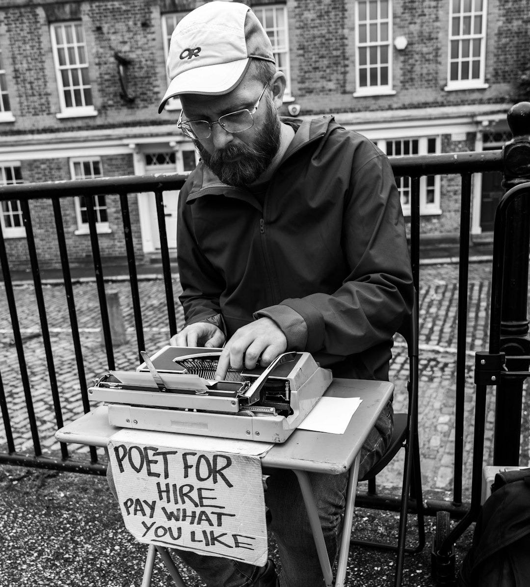 grayscale photography of man sitting and using typewriter