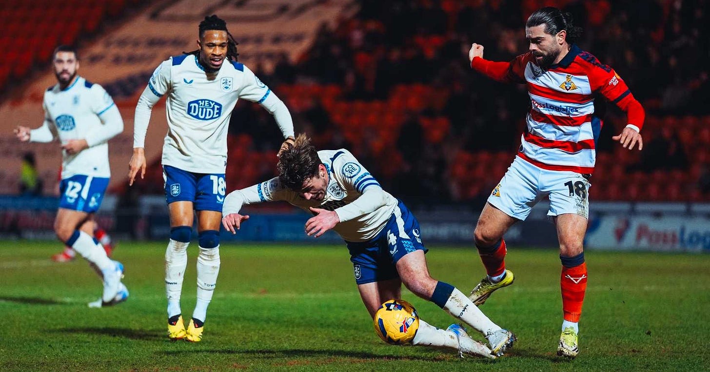 A Doncaster Rovers player tackles a Huddersfield Town player.