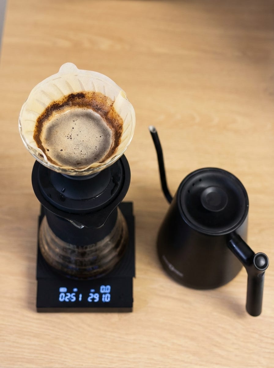 Pour-over coffee brewing in a Hario Switch dripper on a digital scale, with a gooseneck kettle nearby.
