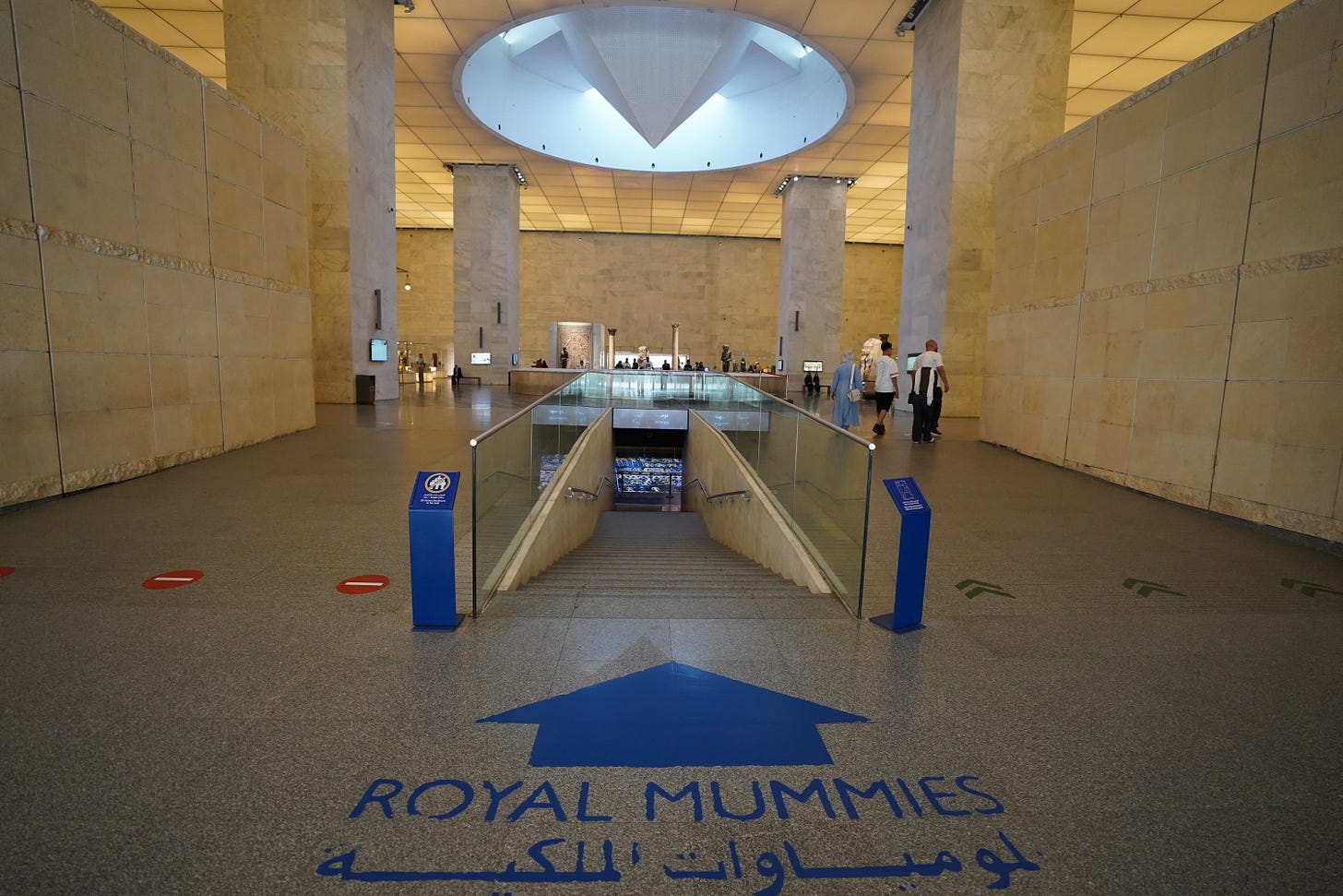 The entrance stairway to the Royal Mummies Hall at Cairo’s National Museum of Egyptian Civilization, with a blue arrow and the words Royal Mummies in English and Arabic.