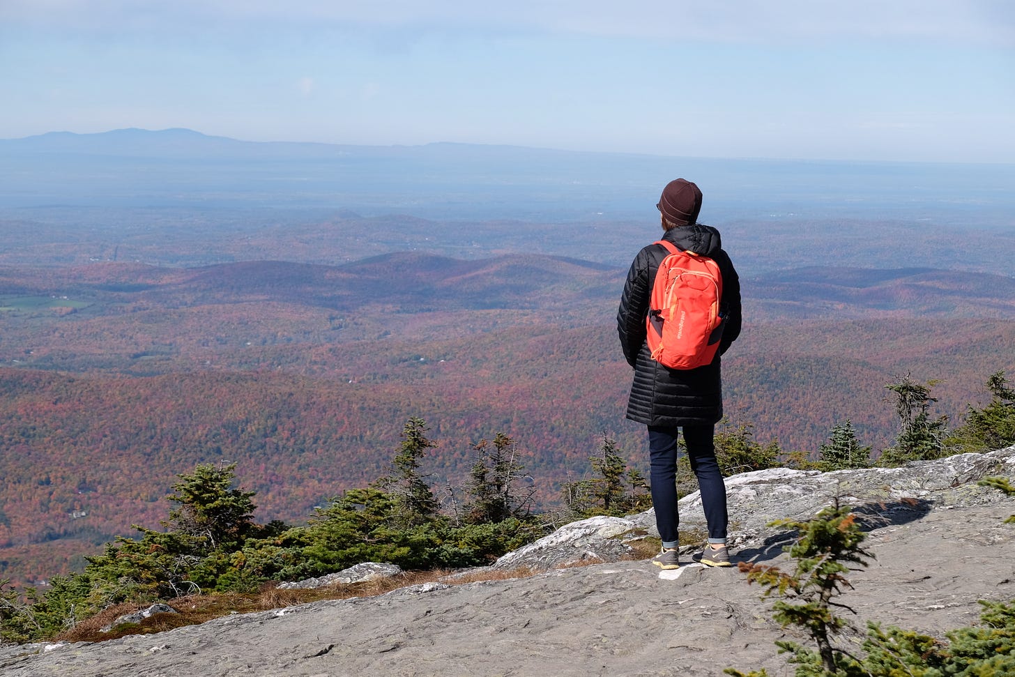 author atop a mountain looking out over the hills of Vermont