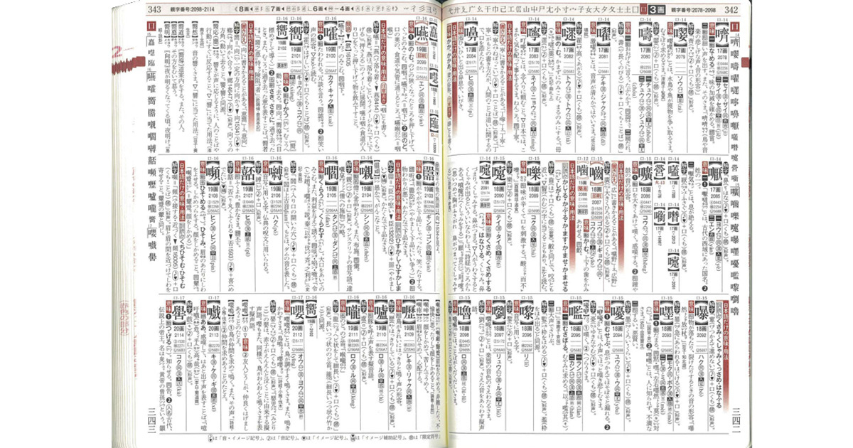 Imagem das páginas brancas abertas de um livro, ilustradas com caracteres japoneses escritos em preto com destaques em vermelho.