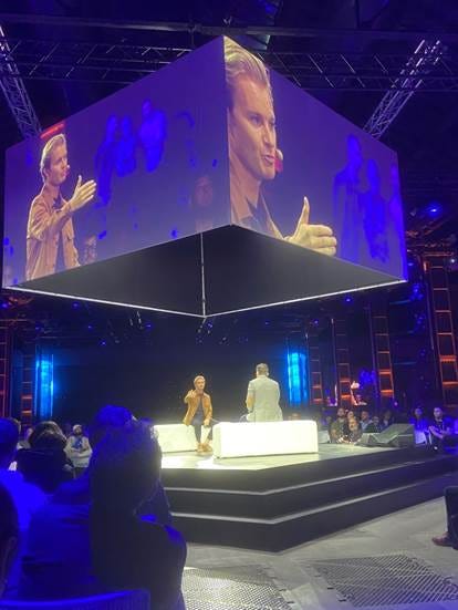 A stage with a large screen

AI-generated content may be incorrect.