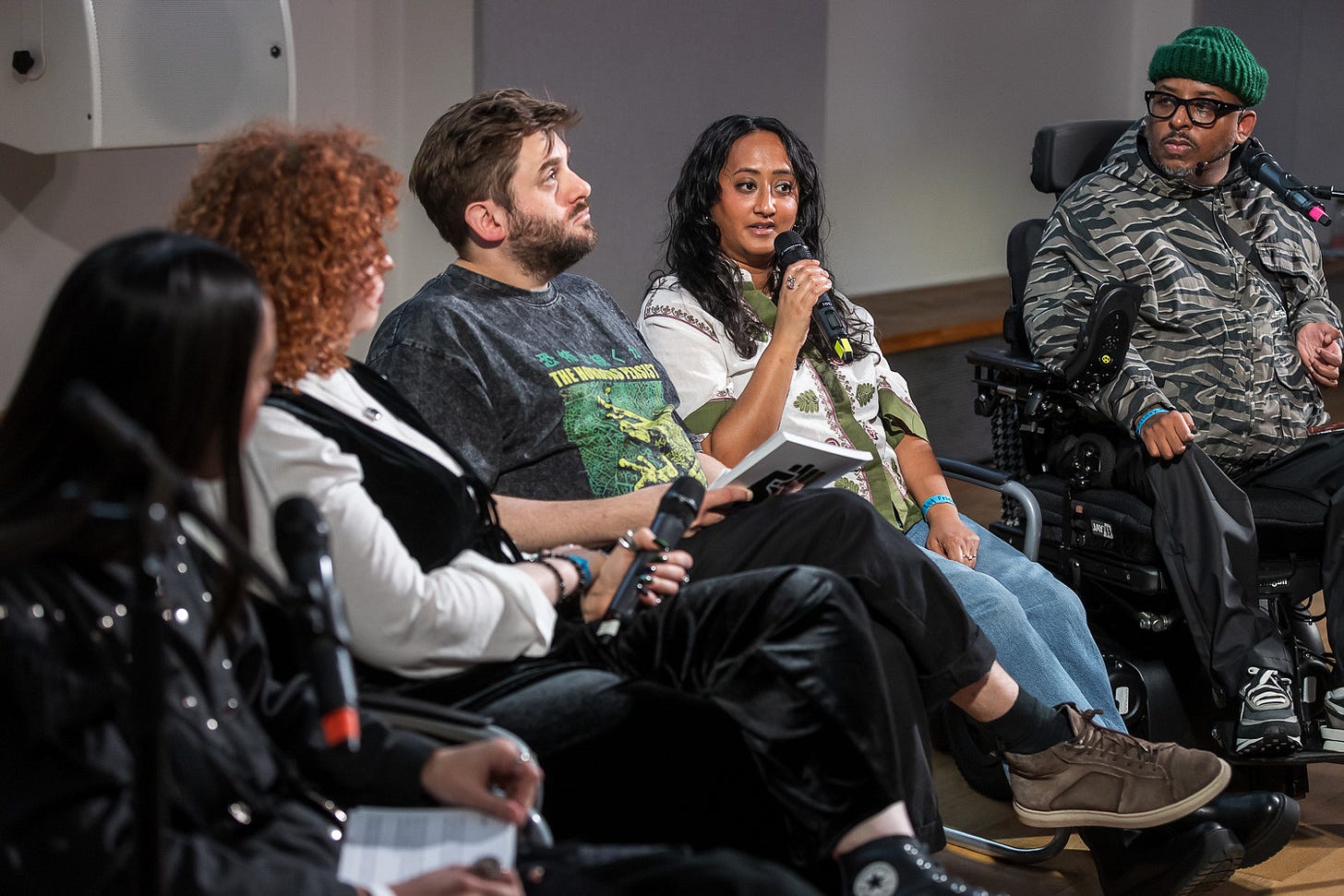 From left to right, Claudia, Zuleika, Mark, Sabrina and Chris on the panel talk. Sabrina holds the microphone to her mouth and is speaking. 