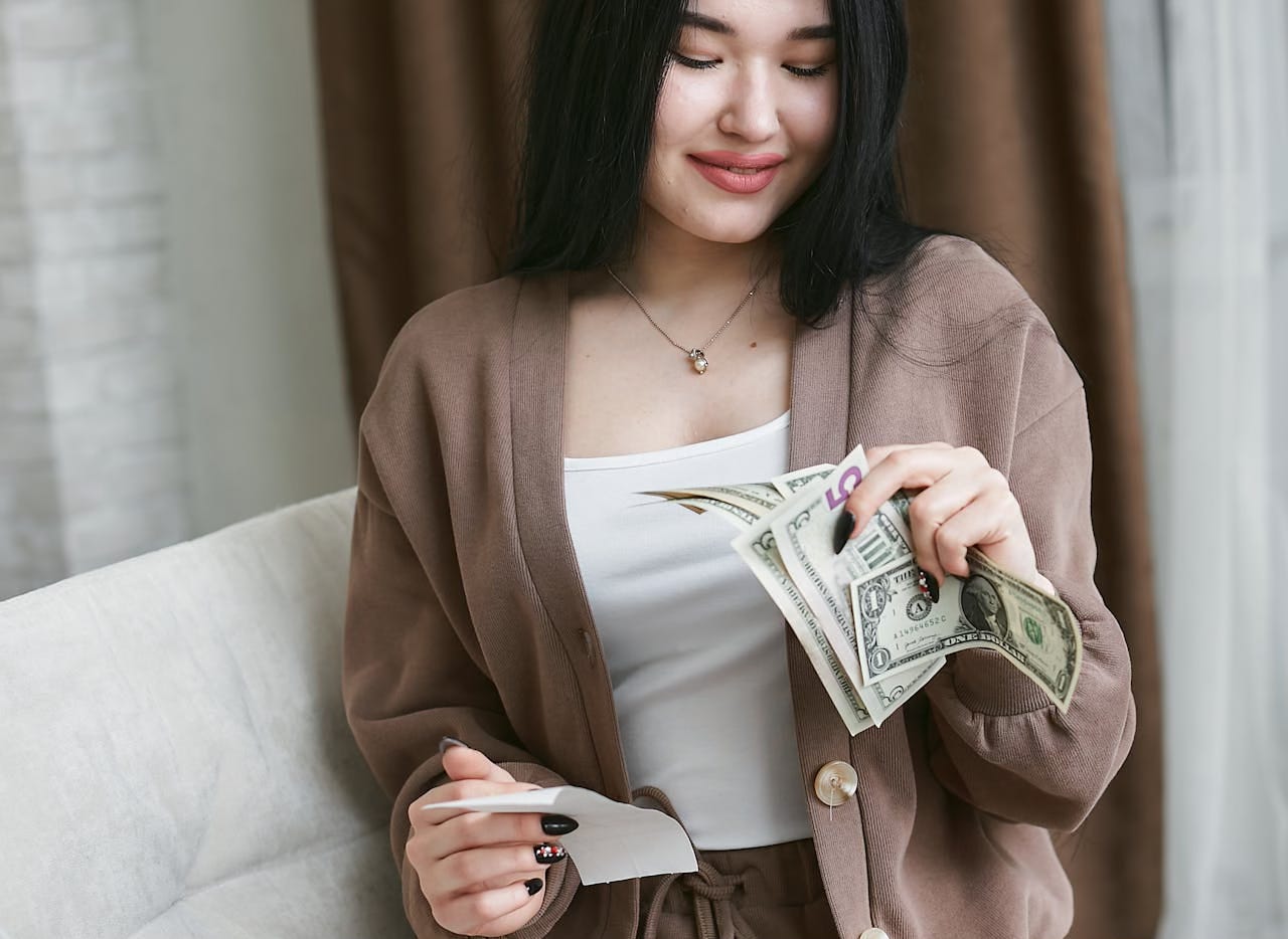 Woman with dark hair holding a receipt in one hand and money in the other. Woman with dark hair holding a receipt in one hand and money in the other.