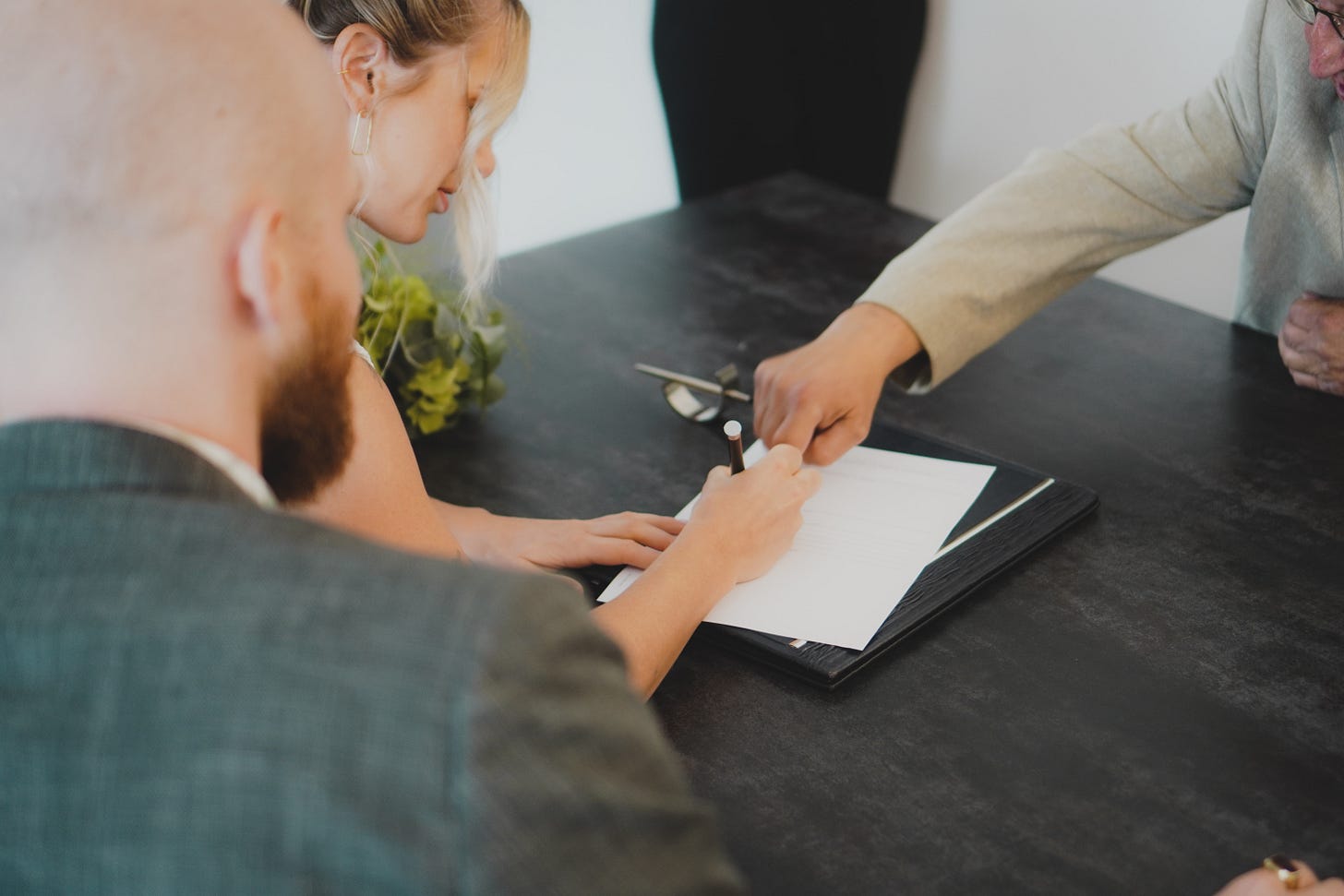 People sat around a table. A person is signing a letter.