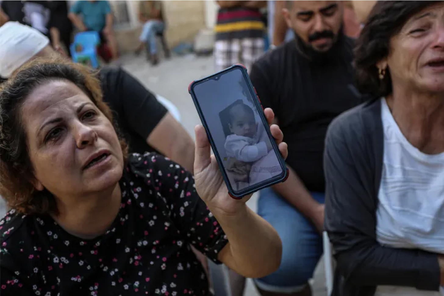 A woman shows a picture of a baby, George Ramez al-Souri, one of the 18 dead following an Israeli air strike on the Orthodox church in Gaza City [Abdelhakim Abu Riash]