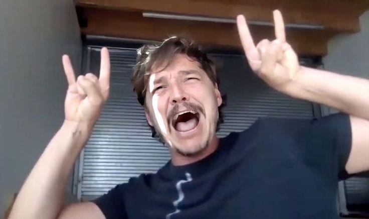 This may contain: a man with his hands in the air making two fingers up and one eye open