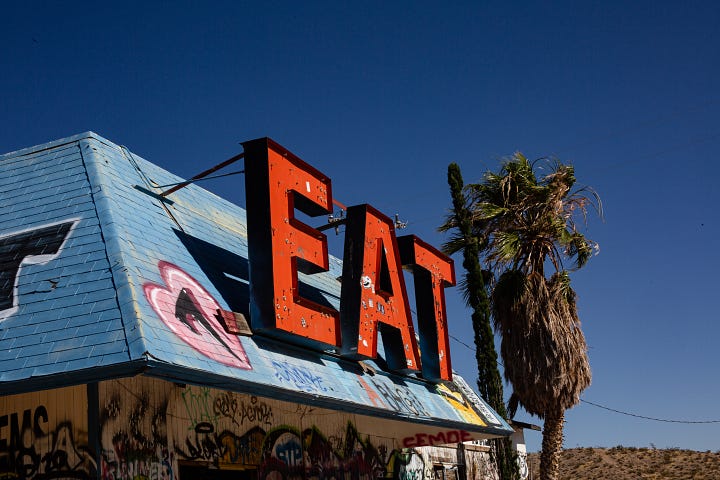 The first image shows an old store front with the word "EAT" in red block letters on a building with graffiti and a palm tree blowing behind it. The second image depicts graffiti that reads "You're a bandit like me, eyes full of stars" above a painting of a bison skull outlined in red.