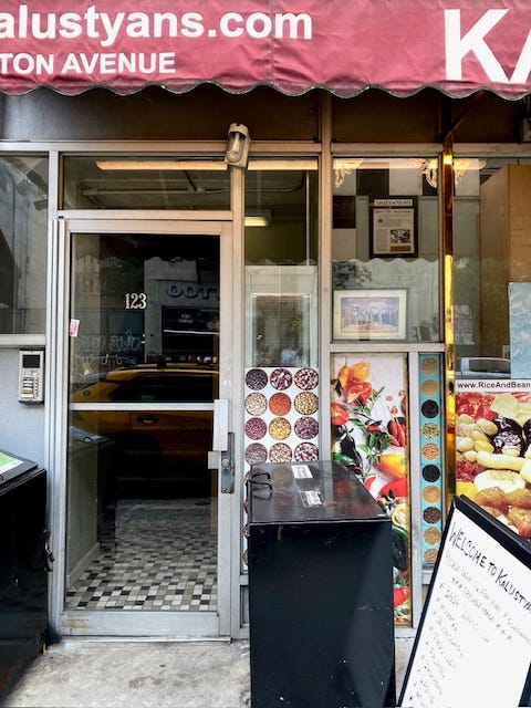 The entrance to the apartments at 123 Lex. Next to the door is a plaque behind glass, surrounding by photos of spices and produce.
