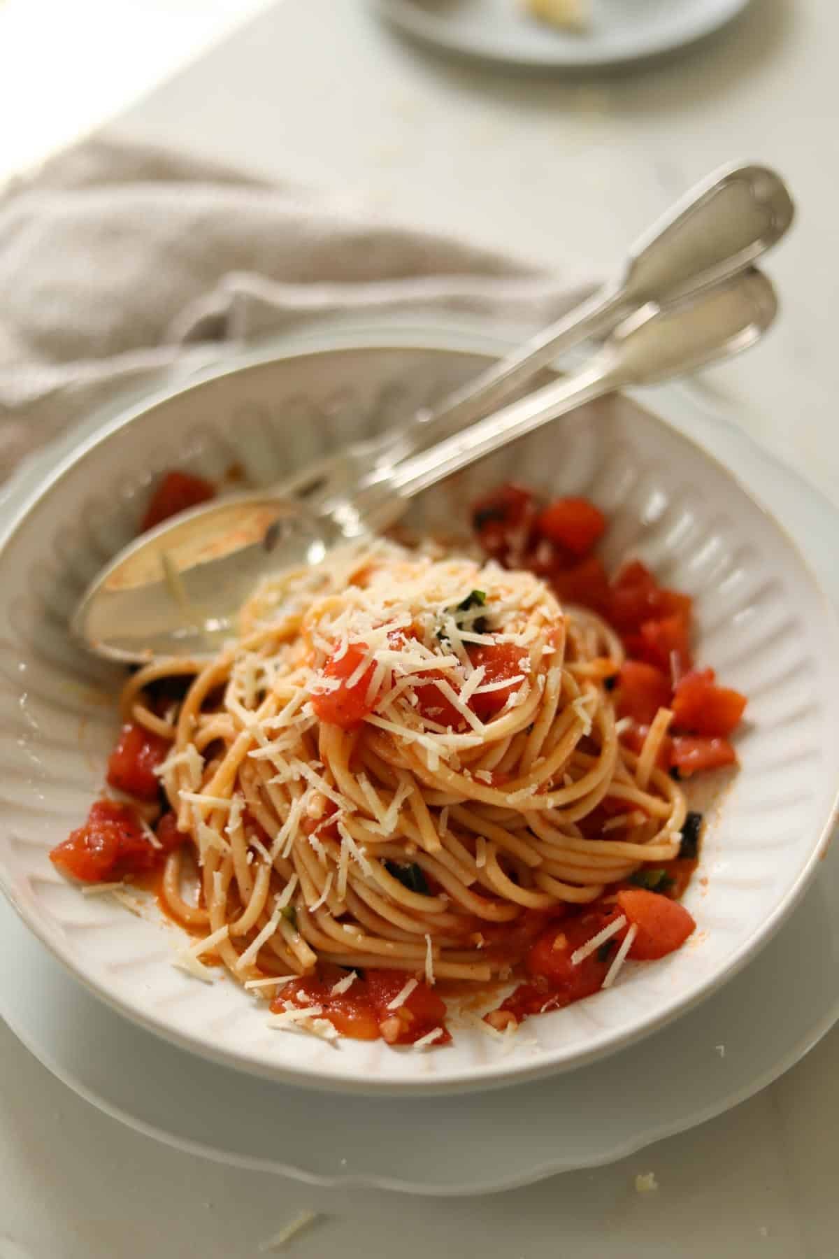 a bowl of pasta with fresh tomato sauce topped with freshly grated parmesan cheese.