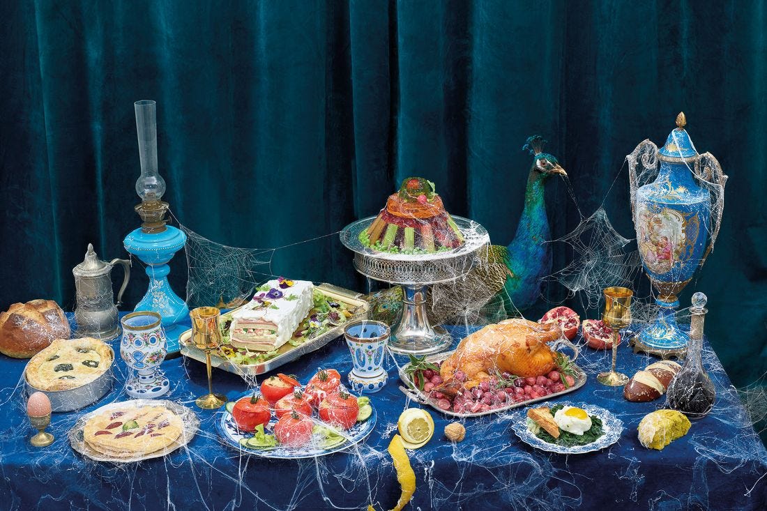 Image shows a table covered with food in fancy seeming vessels. It is covered in cobwebs. Image shows a table covered with food in fancy seeming vessels. It is covered in cobwebs.