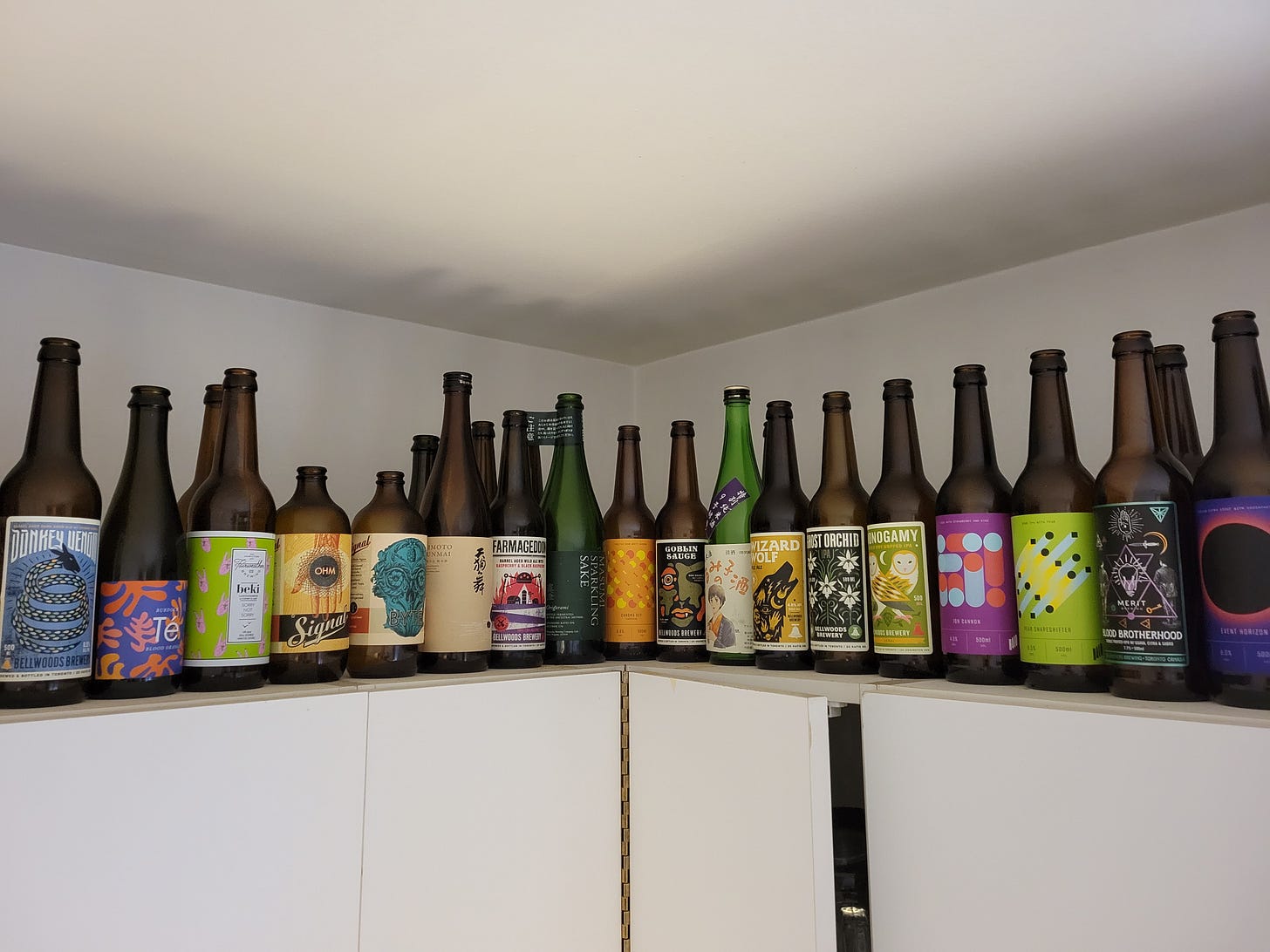 a series of empty, local beer bottles sitting on top of cupboards