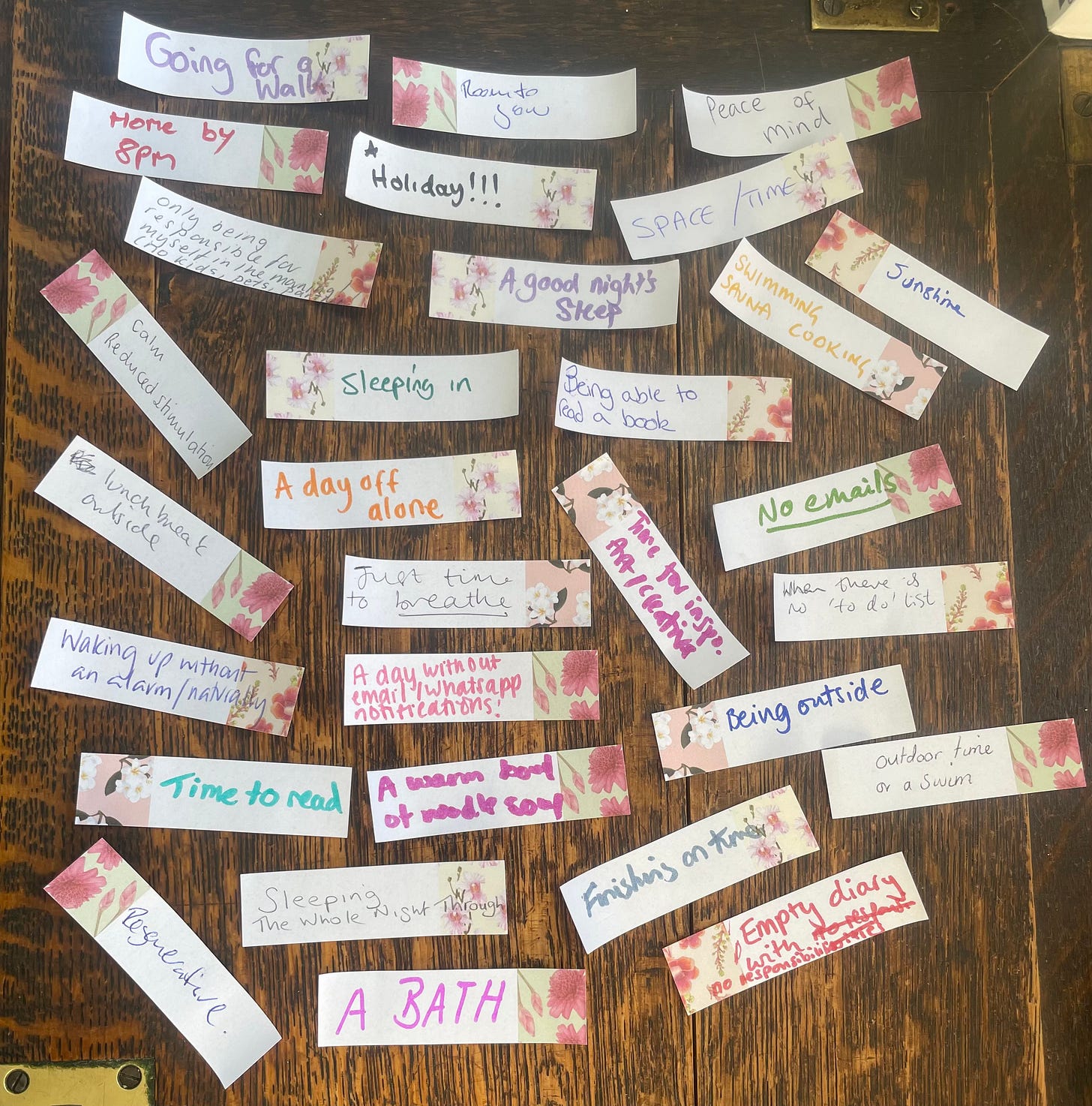 About twenty small slips of paper on a table, each giving a different answer to 'what rest looks like', including sleep, being outside, and time to breathe
