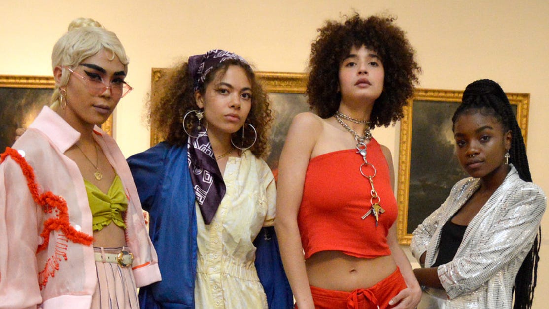 A photo of 4 Queer youth from the museum dressed in bright color outfits all looking into the camera
