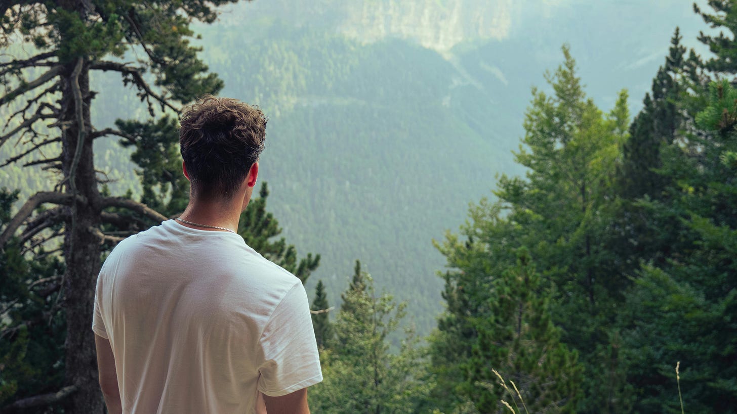 Mann steht mit dem Rücken zur Kamera vor einem Ausblick auf die Natur. Mann steht mit dem Rücken zur Kamera vor einem Ausblick auf die Natur.