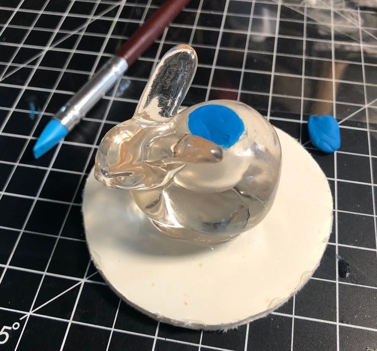 Mounting the bunny on the base and filling in the candle hole with clay.