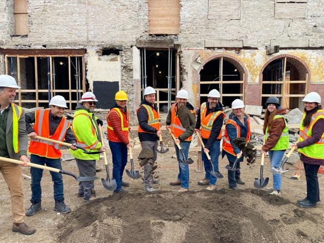 Heritage Flats ground breaking with many people in safety vests holding shovels