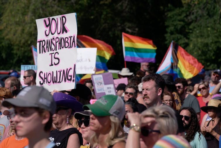 A protester holds up a sign that reads Your Transphobia is Showing. A protester holds up a sign that reads Your Transphobia is Showing.