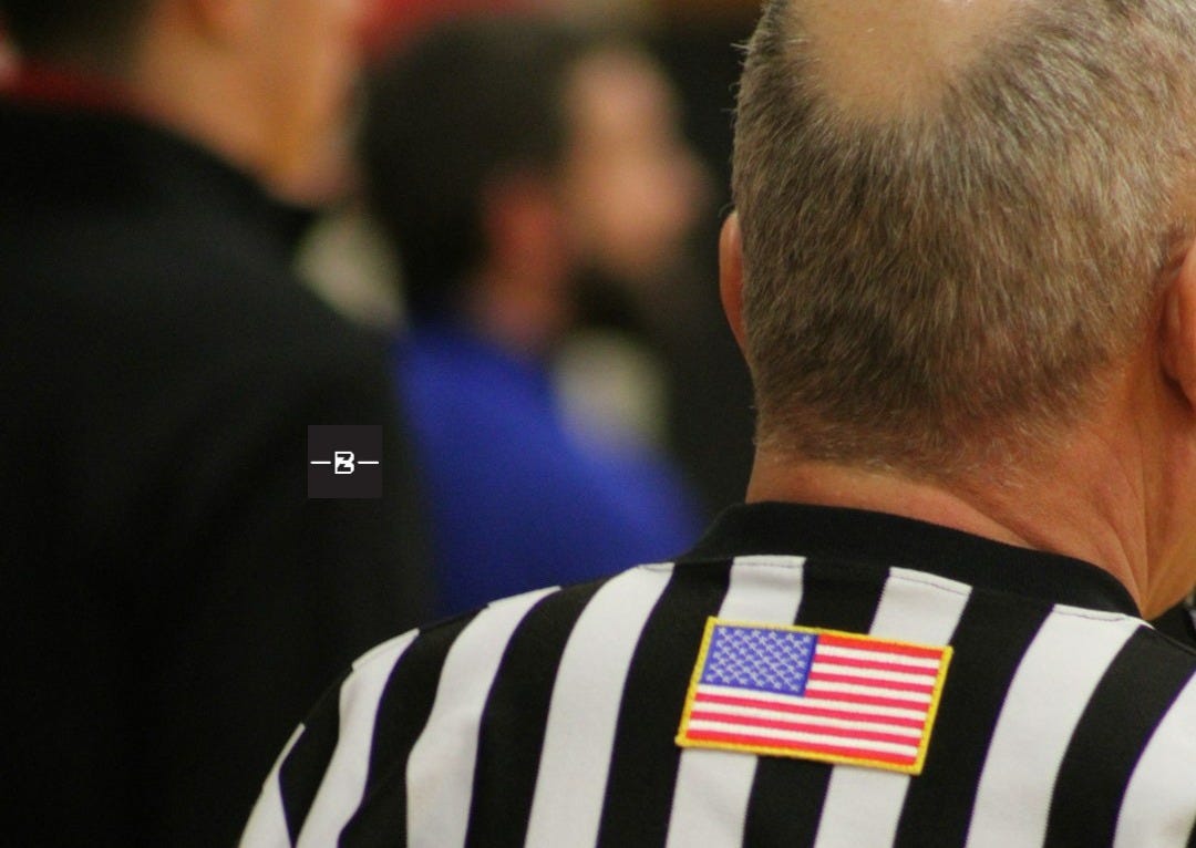 a man in a referee's uniform with an american flag patch on his back a man in a referee's uniform with an american flag patch on his back