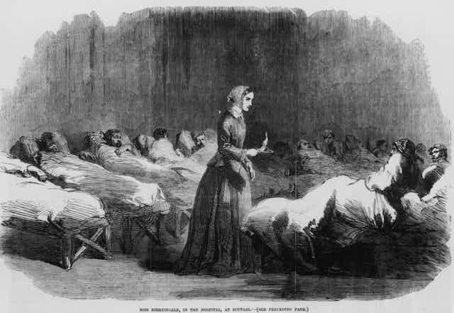 Illustration of English nurse Florence Nightingale overseeing patients lying in beds in a hospital. Illustration of English nurse Florence Nightingale overseeing patients lying in beds in a hospital.