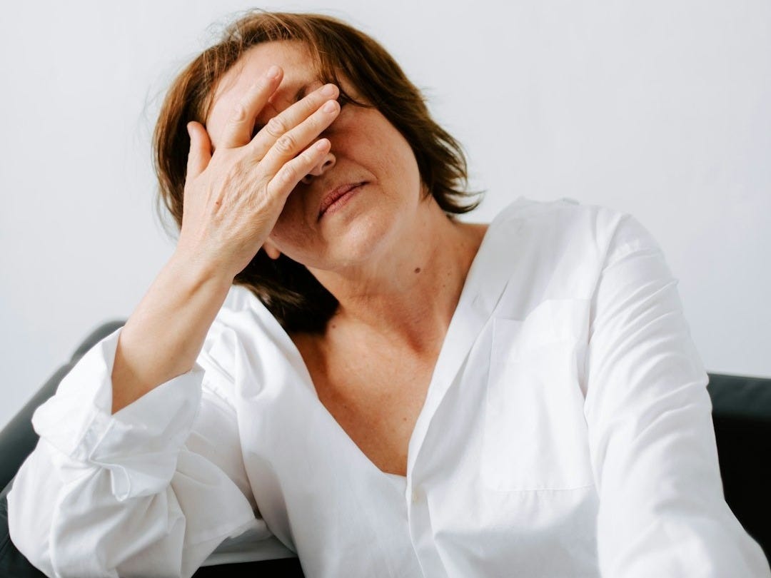 a woman sitting on a couch holding her hands to her face a woman sitting on a couch holding her hands to her face