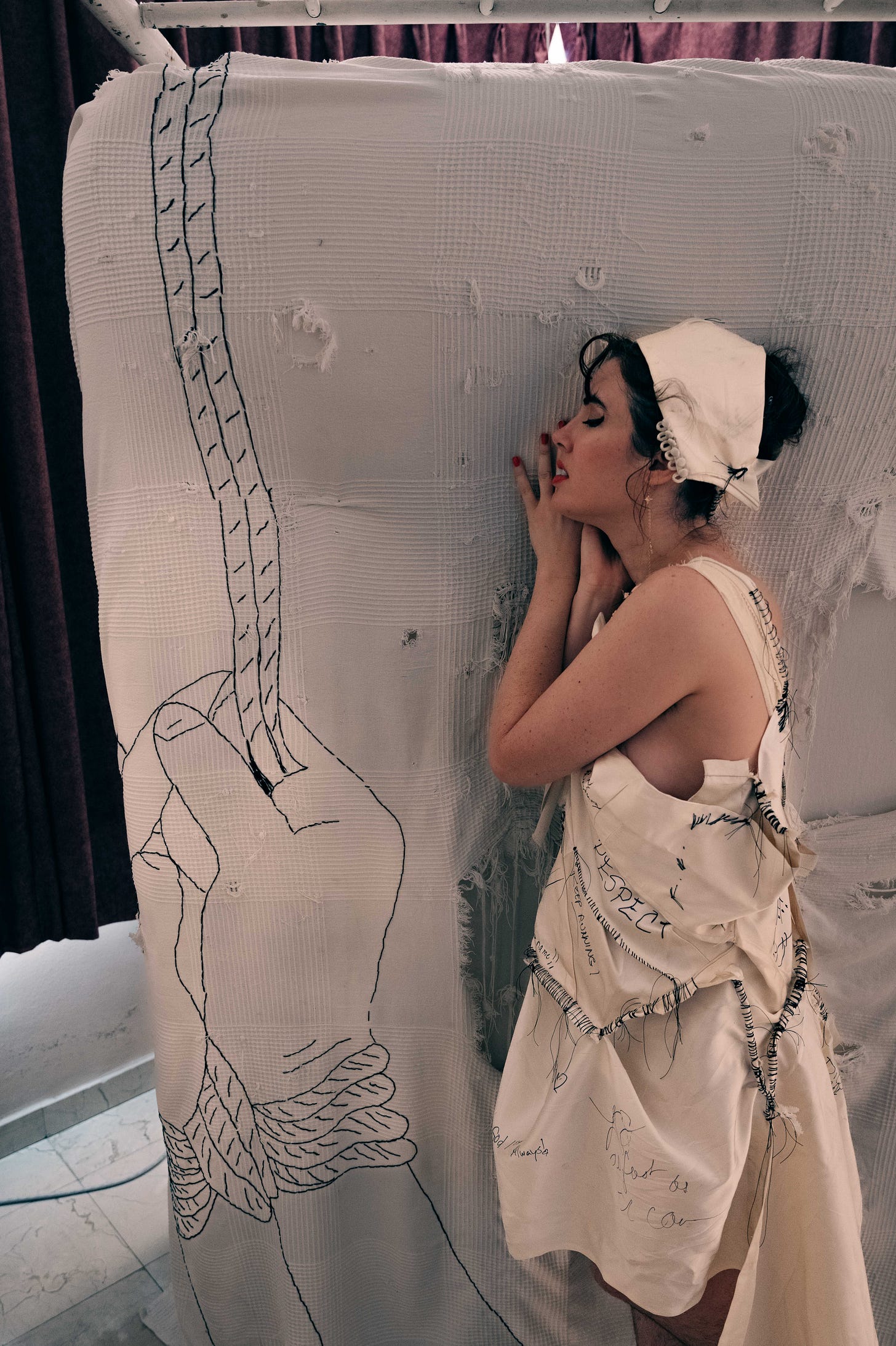 girl in white dress lies against an upright bed with stitching design on quilt