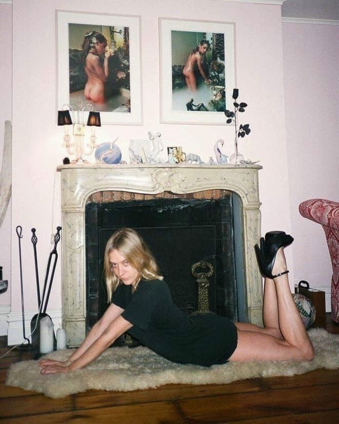 This may contain: a woman laying on the floor in front of a fire place with her legs crossed